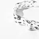 Pulsera rígida plateada con textura irregular y diseño orgánico.