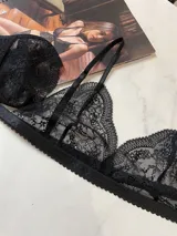 Conjunto de lencería de tres piezas en encaje negro. Incluye bralette con breteles regulables y collarín integrado, y tanga regulable con corte media less.