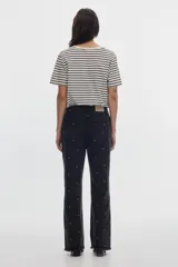 Jean flare de tiro medio, color negro con efecto gastado y estampado de lunares metalizados distribuidos por toda la prenda.