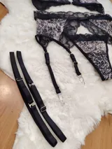 Conjunto de lencería compuesto por corpiño triangular, bombacha tipo colaless y portaligas, confeccionado en encaje negro con estampado animal print.