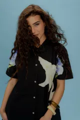 Vestido midi negro con estampado de flores y bichos en tonos celeste y blanco, con cuello camisero y botones frontales.