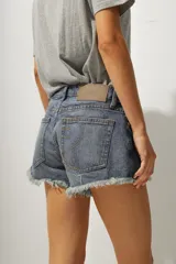 Short de jean de tiro medio con ruedo desflecado y cierre frontal con botón y cremallera.