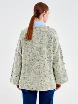 Saco de punto estilo kimono con mangas amplias y silueta relajada. Presenta un cierre frontal mediante un gancho metálico y está confeccionado en una mezcla de lana, nylon y viscosa con una textura moteada.