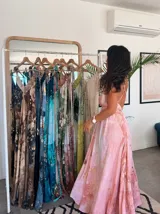 Vestido largo sin mangas con escote en V pronunciado, de corte amplio y fluido, con estampado abstracto en tonos rosados, marrones y blancos, y un cordón trenzado ajustable en la cintura.