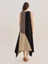 Vestido midi de lino con diseño geométrico en bloques de color negro, marrón y beige, cuello redondo, sin mangas y dobladillo asimétrico en punta.