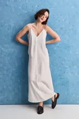 Vestido largo blanco de corte amplio y silueta recta, confeccionado en mezcla de lyocell, viscosa, nylon y lino. Tiene escote en V y breteles finos regulables.