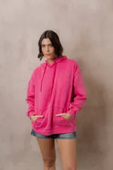 Canguro oversize fucsia con efecto washed, capucha con cordones ajustables al tono, bolsillo frontal tipo canguro y terminaciones de rib en puños y cintura.