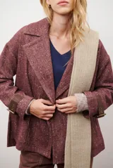 Chaquetón de lana color bordó con diseño de espiga y motas blancas. Tiene solapa, doble abotonadura frontal, mangas largas con detalle de correa y hebilla en los puños.