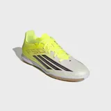 Championes de fútbol sala Adidas F50 Club IN, diseñados para velocidad y precisión. Presentan un exterior de material sintético y malla técnica en color amarillo neón con detalles en blanco y negro, incluyendo las icónicas tres tiras de la marca. Cuentan con lengüeta flotante transpirable y suela de caucho de alta tracción que no deja marcas, ideal para superficies interiores.