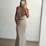 Conjunto de dos piezas color beige, compuesto por un top halter con escote drapeado y una falda larga de corte recto y tiro alto.