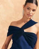 Mono largo de vestir azul marino, con escote bardot, detalle de nudo en la parte delantera y capa de tul transparente que cae desde el hombro.