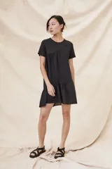 Vestido negro corto con cuello redondo, mangas cortas y falda con volantes.