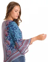Blusa de gasa con estampado floral y geométrico en tonos azules, rojos y celestes. Presenta cuello a la base, mangas tres cuartos amplias y un corte asimétrico en el ruedo.