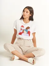 Remera blanca de corte oversized con estampado de figuras femeninas abstractas en colores rojo, marrón, celeste y lila.