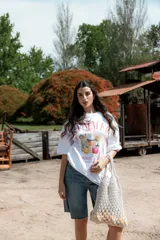 Remera blanca de algodón con cuello redondo y mangas cortas. Estampado frontal con diseño de cócteles y texto "Summer Babe Cocktail Club and Chill".