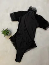 Body negro de lycra entallado con detalles de microtul y encaje, cuello alto y espalda descubierta.