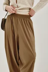 Pantalón tipo babucha de corte holgado y tiro alto, con cintura elástica y diseño de pierna amplia que se estrecha hacia los tobillos.