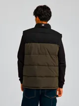 Chaleco puffer Caterpillar Arctic Zone Vest, modelo bicolor con parte superior negra y parte inferior en verde militar, cuello alto y cierre frontal con cremallera.