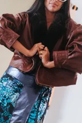 Campera de cuero oversize con solapa amplia de corderito, mangas anchas y detalle de cuero trenzado en la parte delantera.