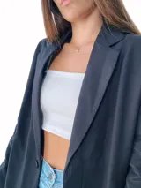 Blazer negro de corte recto y largo, con solapas y cierre frontal con dos botones blancos.