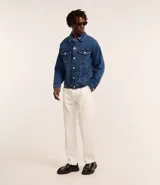 Campera trucker de jean azul oscuro, con cuello tradicional, cierre frontal con botones, cuatro bolsillos y mangas largas.