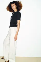 Camiseta de punto ajustada con cuello redondo y manga corta. Presenta detalles de vivos en color blanco a contraste en el cuello y la tapeta frontal, que cuenta con cierre de botones metálicos.