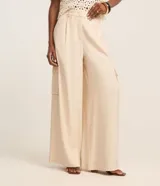 Pantalón pantalona de corte amplio, color beige, con trabillas en la cintura, pliegues delanteros y bolsillos cargo en los laterales.