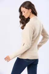 Campera tejida de abrigo color beige, con cierre frontal, cuello alto y bolsillos laterales.