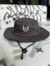 Gorro de pescador gris con logo bordado en blanco en el frente y cordón ajustable.