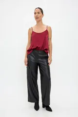 Pantalón cargo de corte recto y tiro medio, confeccionado en eco cuero negro. Presenta bolsillos laterales tipo cargo, cierre frontal con botón y bragueta, y un acabado liso con brillo sutil.