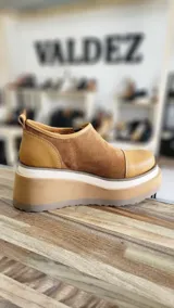Zapatos de cuero color tostado con plataforma alta, cierre frontal y detalles en gamuza y textura símil cocodrilo en tonos dorados.