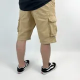 Bermuda de jean color beige con lavado gastado, corte recto y bolsillos cargo laterales.