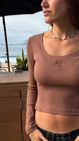 Top de manga larga en tejido acanalado color marrón, con escote redondo y logo bordado a tono en el centro del pecho.