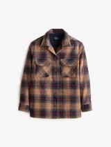 Camisa de lana a cuadros color marrón, azul y rojo, de corte recto con cuello camisero, cierre frontal con botones, dos bolsillos con solapa abotonados en el pecho y mangas largas con puños abotonados.