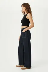 Pantalón jean azul oscuro de corte ancho, tiro medio, con bolsillos delanteros aplicados y costuras pespunteadas en contraste.