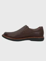 Zapato tipo mocasín Hush Puppies modelo Oregon, confeccionado en cuero vacuno con textura granulada. Presenta un diseño sin cordones con elásticos laterales para un ajuste cómodo, costuras reforzadas y suela de goma EVA de alto rendimiento.