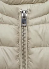 Chaleco corto de diseño recto y cuello redondo, confeccionado en tejido acolchado con acabado repelente al agua. Cuenta con cierre frontal mediante cremallera.