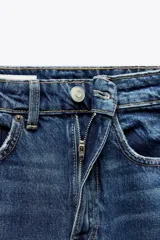 Jeans de tiro alto color negro con efecto lavado, corte mom fit, cinco bolsillos y cierre frontal con cremallera y botón metálico.