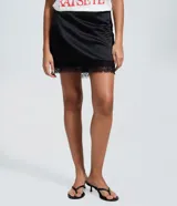 Short pollera de satén negro con acabado brillante, corte ajustado y detalle de encaje floral con transparencia en el ruedo. Cuenta con cierre invisible en la parte trasera.