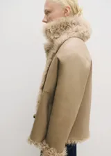 Abrigo corto de piel ovino con diseño reversible y doble faz. Presenta cuello con solapas de muesca, cierre delantero cruzado con botones y mangas largas.