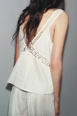 Top blanco de escote pico y tirantes finos, con detalle de encaje a tono y bajo recto.
