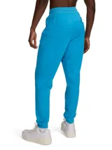 Pantalón de jogging Under Armour, modelo Sportstyle Tricot, color azul brillante. Presenta un diseño deportivo con ajuste cónico, puños elásticos en los tobillos, bolsillos laterales con cierre y logo de la marca estampado en el muslo derecho.