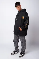 Buzo canguro gris claro de corte oversize, con capucha y cordones negros con letras blancas. Presenta un bolsillo tipo canguro y un estampado pequeño en el pecho y otro en la manga.