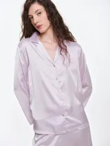 Camisa de dormir de satén con cuello solapa y cierre frontal de botones. Presenta un corte holgado y mangas largas, ofreciendo una caída suave y ligera sobre el cuerpo.