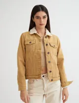 Campera de gabardina color mostaza, forrada con corderito color crudo en el cuerpo y cuello. Tiene corte clásico y botones metálicos personalizados.