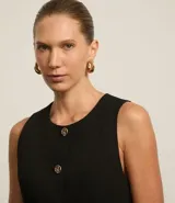 Chaleco negro de corte sastrero, con cuello redondo y botones metálicos.