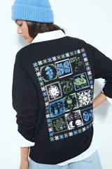 Remera de manga larga negra con cuello redondo y puños blancos visibles, presentando un estampado gráfico con motivos celestiales en el pecho.