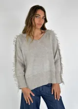 Sweater beige de lino con escote en V y mangas largas con flecos.