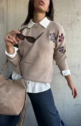 Sweater de punto color beige con cuello redondo y diseño de flores bordadas en tonos oscuros en el frente y las mangas.