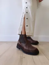 Bota Chelsea de cuero color marrón chocolate con elástico lateral negro y suela track color negro.